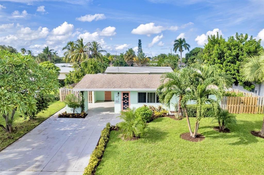 A single-story house with a light green exterior, a paved driveway, and lush tropical landscaping — 2611 NE 20th Street, Pompano Beach FL 33062, POMPANO BEACH, FL