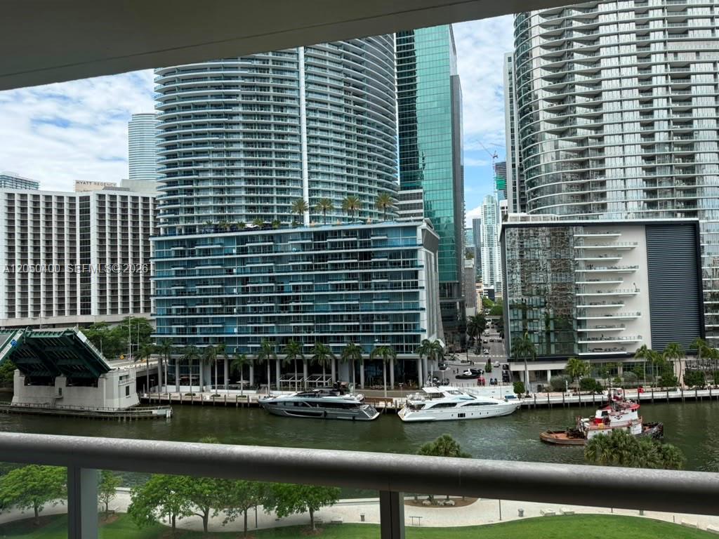 A view from a balcony overlooking a river, boats, and modern high-rise buildings — 475 Brickell Ave # 1012, Miami FL 33131, MIAMI, FL