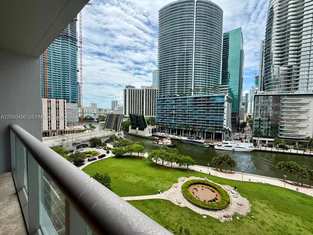 A balcony view overlooks a city park, a river with a drawbridge, and tall skyscrapers — 475 Brickell Ave # 1012, Miami FL 33131, MIAMI, FL