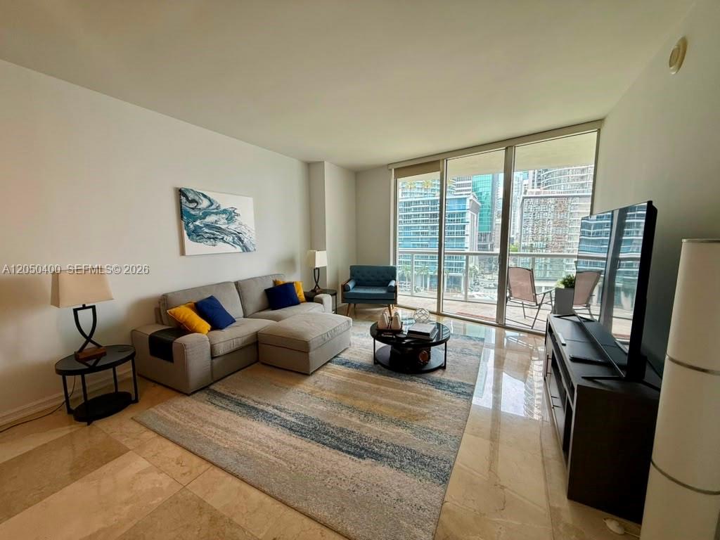 A living room features a sectional sofa, area rug, and balcony access with city views — 475 Brickell Ave # 1012, Miami FL 33131, MIAMI, FL