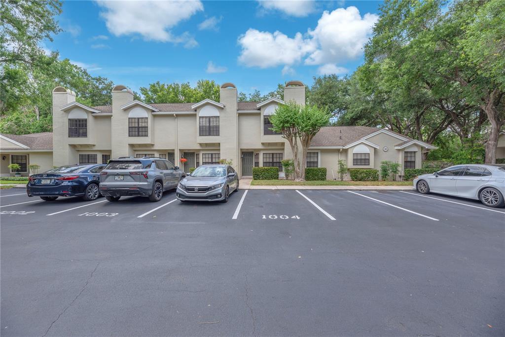 A two-story apartment building features a parking lot with numbered spaces in the foreground — 5100 BURCHETTE ROAD UNIT 1004, TAMPA, FL