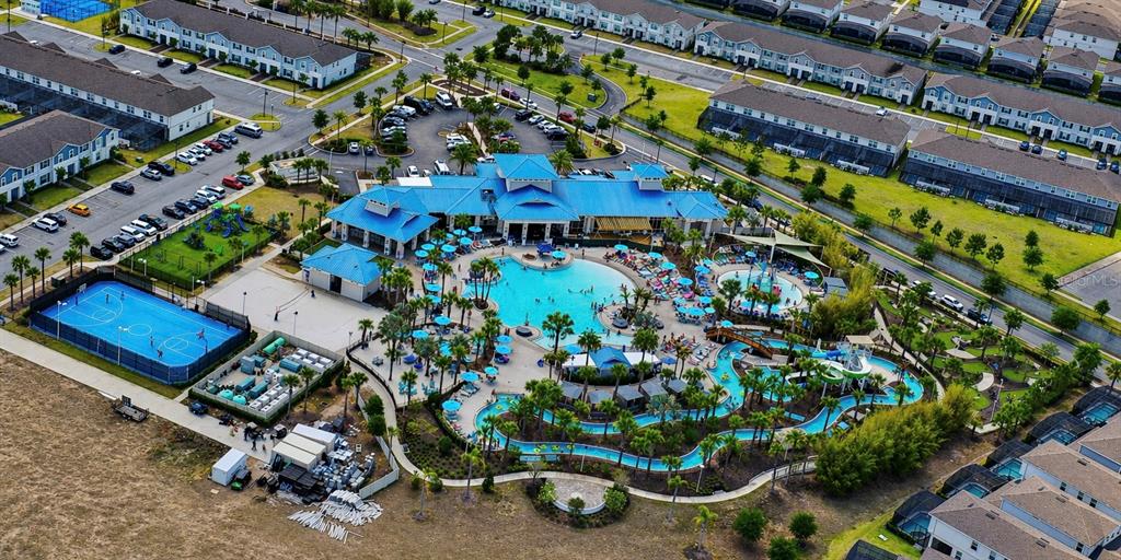 An aerial view shows a community clubhouse with a large pool, lazy river, and courts — 2370 SALTY WINDS WAY, KISSIMMEE, FL