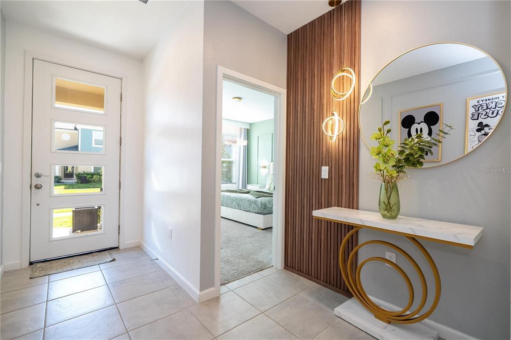 A foyer features a white front door, a wood-slat accent wall, and a marble console table — 2370 SALTY WINDS WAY, KISSIMMEE, FL