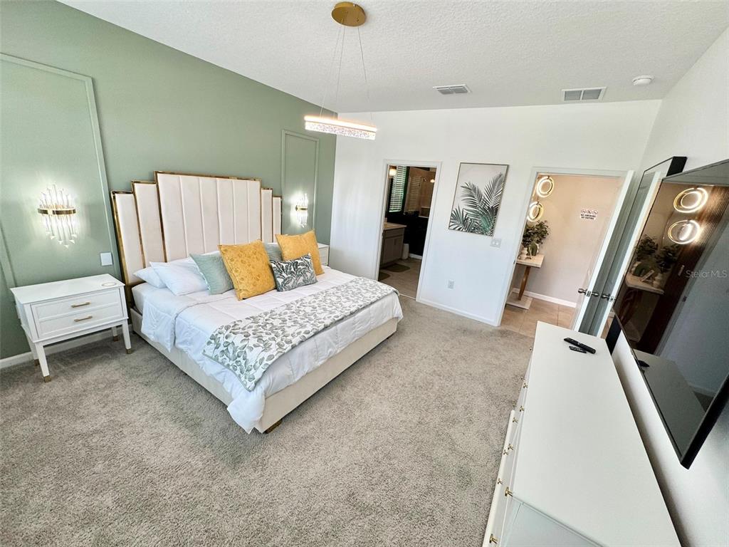 A bedroom features a green accent wall, a large upholstered headboard, and a television — 2370 SALTY WINDS WAY, KISSIMMEE, FL