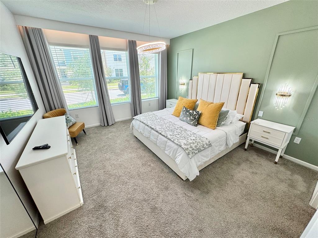 A bedroom features a green accent wall, a tufted headboard, and a white dresser — 2370 SALTY WINDS WAY, KISSIMMEE, FL