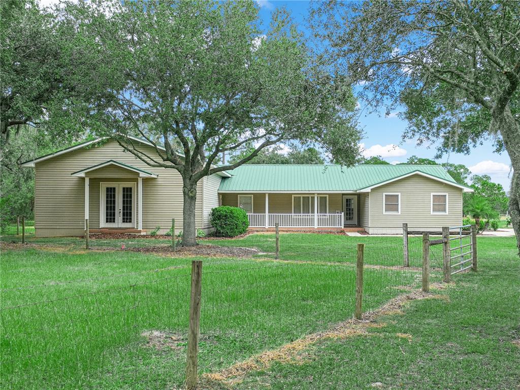 A single-story house with a green metal roof and a detached carport on a lawn — 3963 MAMMOTH GROVE ROAD, LAKE WALES, FL