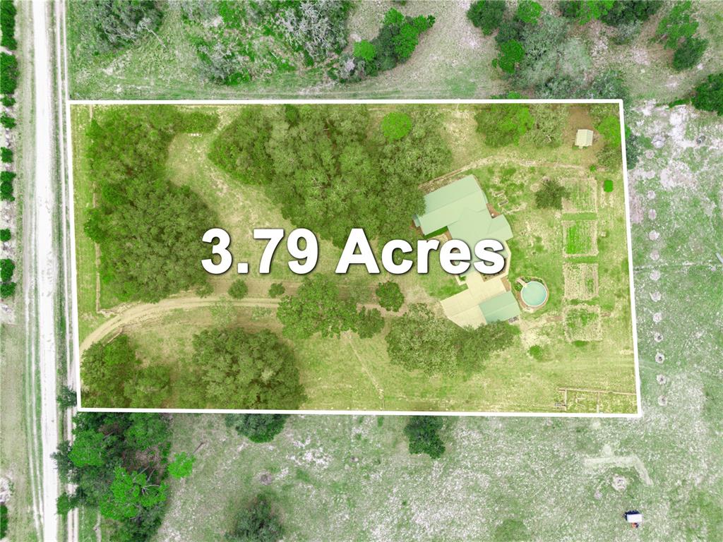A single-story house with a green metal roof and a fenced yard at sunset — 3963 MAMMOTH GROVE ROAD, LAKE WALES, FL