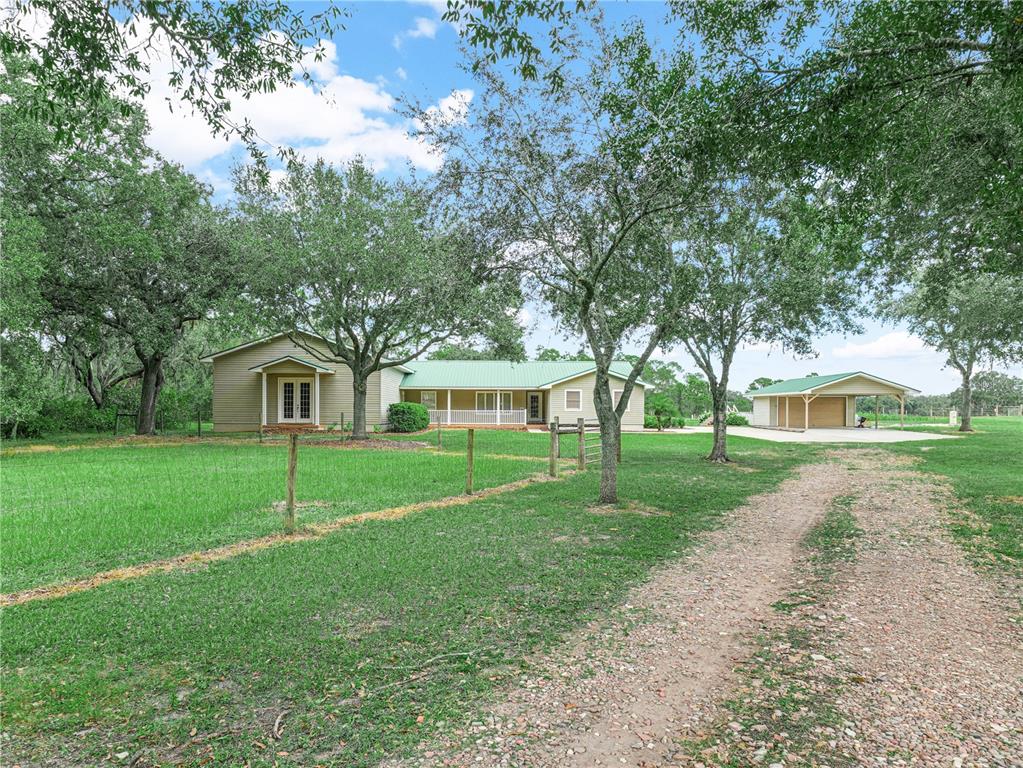 A single-story house with tan siding and a green metal roof sits behind a fence — 3963 MAMMOTH GROVE ROAD, LAKE WALES, FL