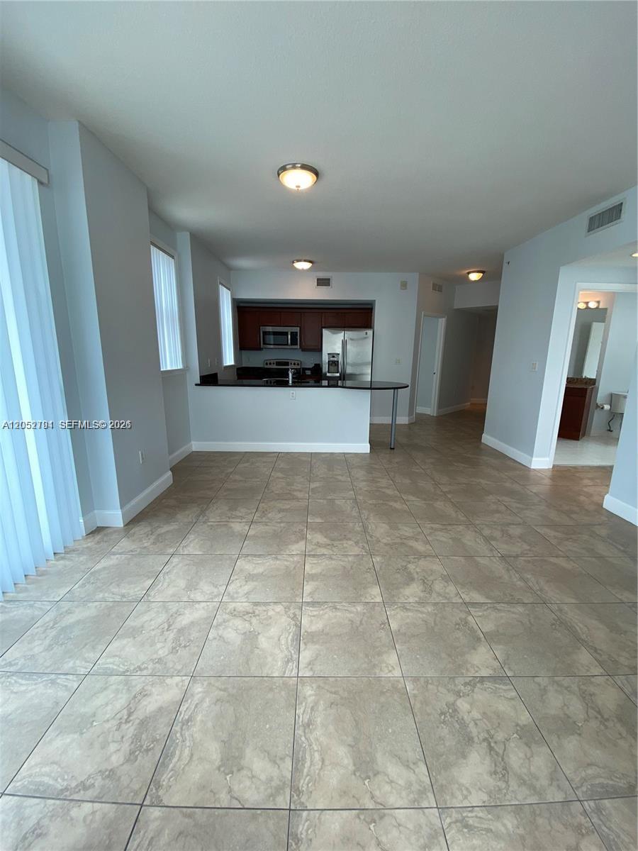 An open-concept living area features light-colored tile flooring and a kitchen with dark cabinets — 7280 SW 90th St # 501, Miami FL 33156, MIAMI, FL
