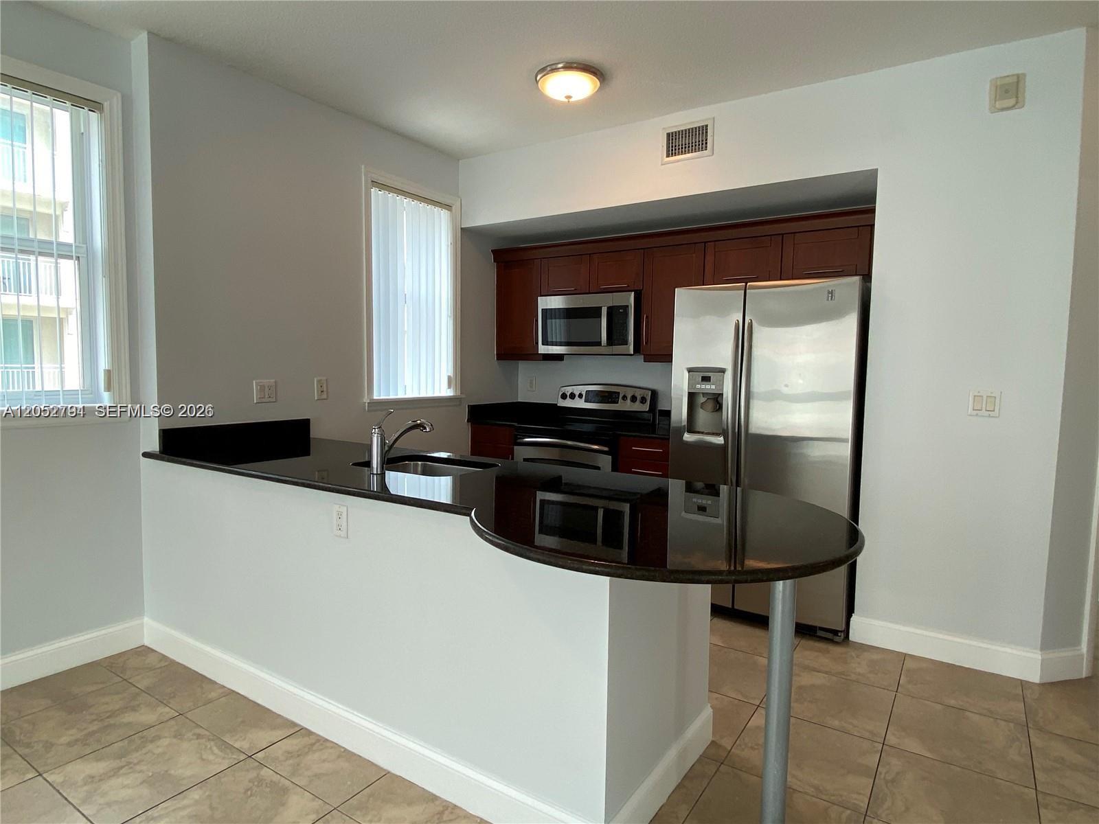 A kitchen features dark wood cabinets, black granite countertops, and stainless steel appliances — 7280 SW 90th St # 501, Miami FL 33156, MIAMI, FL