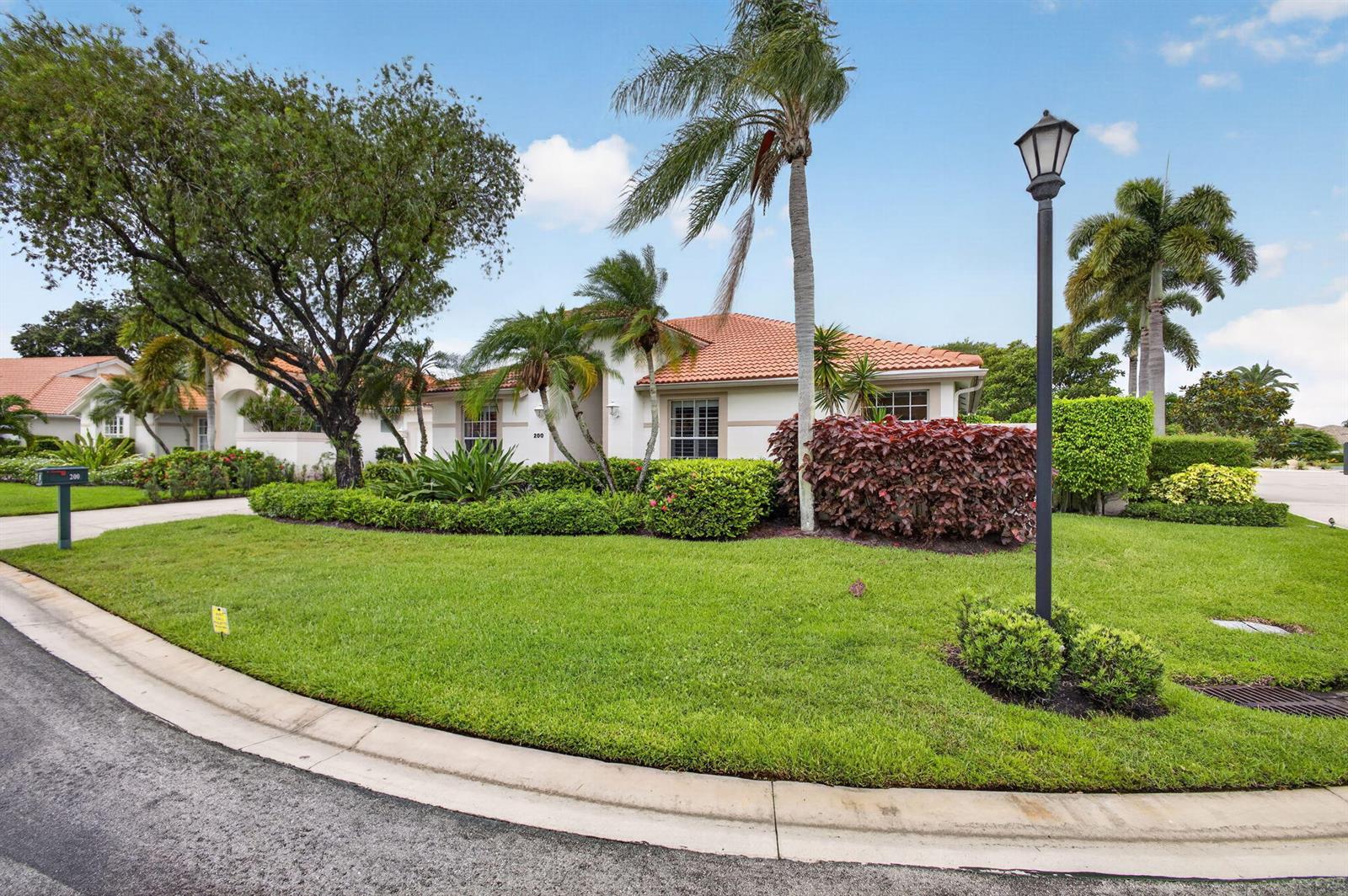 A single-story house with a tile roof and palm trees sits behind a manicured lawn — 200 Eagleton Estates Boulevard, Palm Beach Gardens FL 33418, PALM BEACH GARDENS, FL