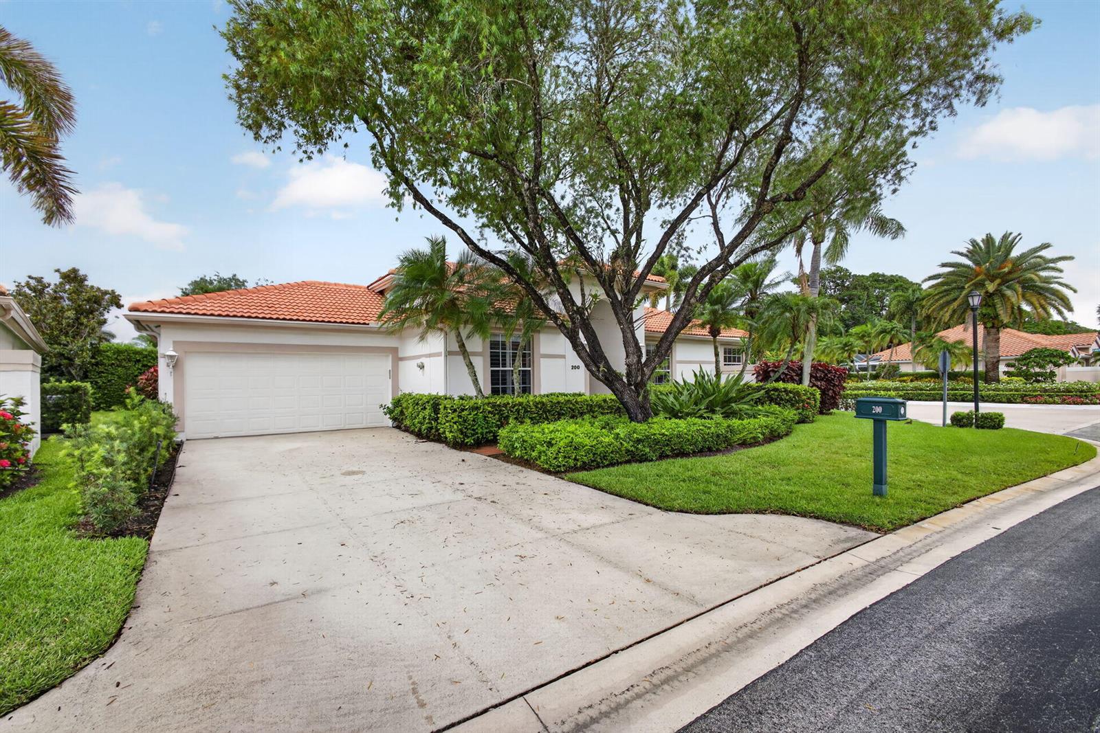 A single-story house with a white exterior, orange tile roof, and a large front tree — 200 Eagleton Estates Boulevard, Palm Beach Gardens FL 33418, PALM BEACH GARDENS, FL
