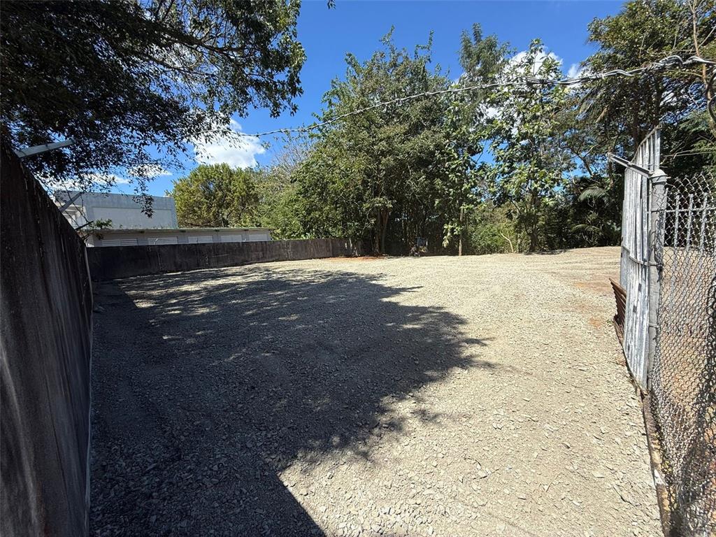 An outdoor gravel lot is enclosed by a concrete wall and a chain-link fence — SECTOR LA ALDEA, BAYAMON, PR