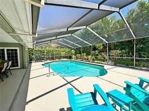 A screened-in patio features a swimming pool, lounge chairs, and a view of lush greenery — 4884 MARSH FIELD ROAD, SARASOTA, FL