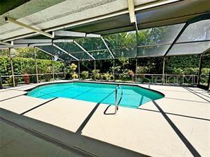 A screened-in swimming pool sits on a patio surrounded by lush green landscaping — 4884 MARSH FIELD ROAD, SARASOTA, FL