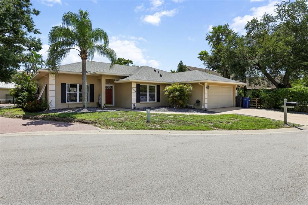 A single-story tan house with a palm tree, a two-car garage, and a red door — 4919 32ND AVENUE DRIVE W, BRADENTON, FL