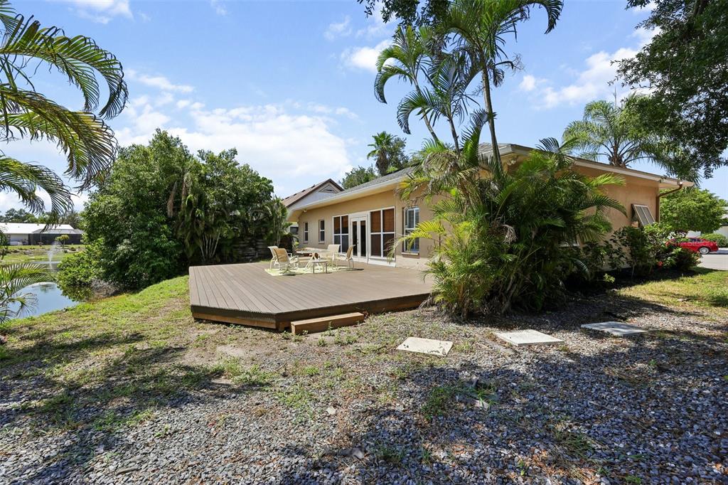 A tan house with a large wooden deck overlooks a pond and palm trees — 4919 32ND AVENUE DRIVE W, BRADENTON, FL