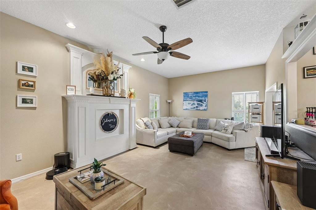 A living room features a white fireplace, a large sectional sofa, and a ceiling fan — 4919 32ND AVENUE DRIVE W, BRADENTON, FL