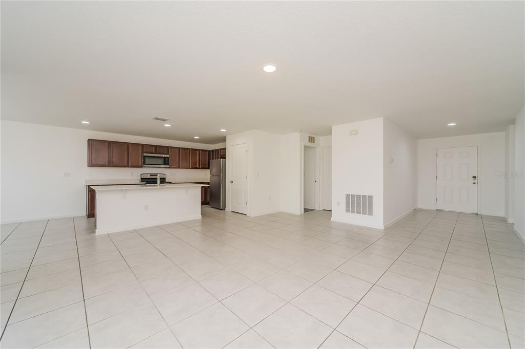 An open-concept kitchen and living area features white tile flooring, dark wood cabinets, and appliances — 1373 LUCERNE LOOP ROAD NE, WINTER HAVEN, FL