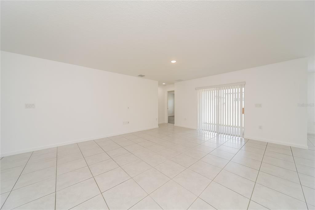 An empty room with white walls, light-colored tile flooring, and a sliding glass door — 1373 LUCERNE LOOP ROAD NE, WINTER HAVEN, FL