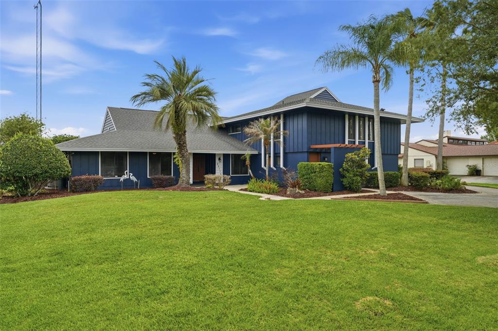 A two-story blue house with a large front lawn and palm trees — 29116 BEAUCLAIRE DRIVE, TAVARES, FL