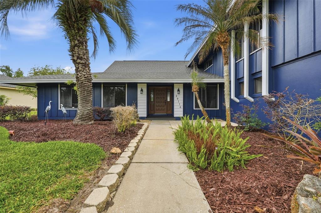 A blue house with a concrete walkway leading to a wooden front door — 29116 BEAUCLAIRE DRIVE, TAVARES, FL
