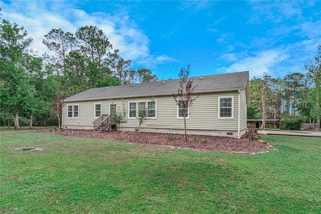 A single-story house with light green siding and a shingled roof sits on a lawn — 3729 HONEY DEW LANE, NEW SMYRNA BEACH, FL