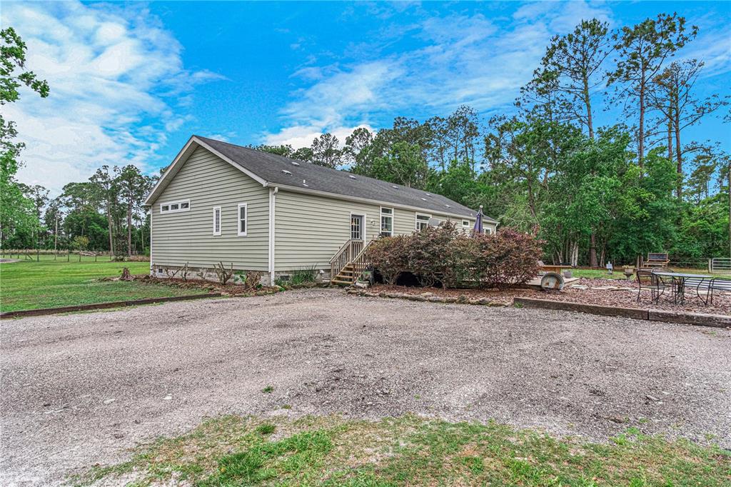 A light green, single-story house with a gravel driveway and a wooden deck — 3729 HONEY DEW LANE, NEW SMYRNA BEACH, FL