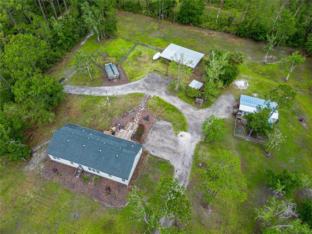 An aerial view shows a house, several outbuildings, and a gravel driveway on a wooded lot — 3729 HONEY DEW LANE, NEW SMYRNA BEACH, FL