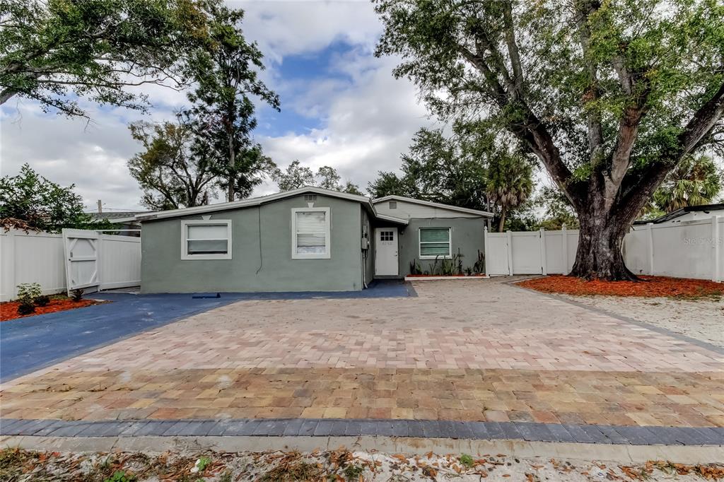 A single-story gray house features a paved driveway and a white vinyl privacy fence — 4532 DEVONSHIRE ROAD, TAMPA, FL