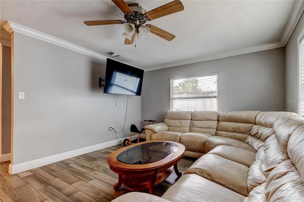 A living room features a large beige sectional sofa, a wooden coffee table, and a wall-mounted television — 4532 DEVONSHIRE ROAD, TAMPA, FL