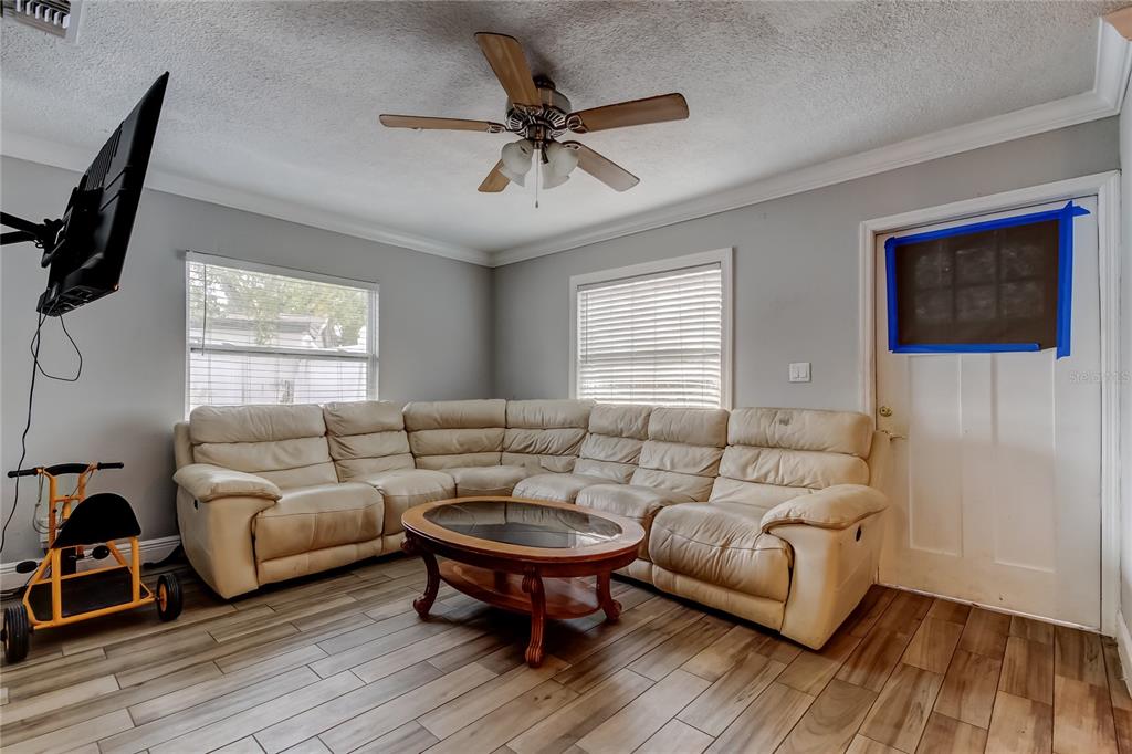 A living room features a beige sectional sofa, a coffee table, and wood-look tile flooring — 4532 DEVONSHIRE ROAD, TAMPA, FL