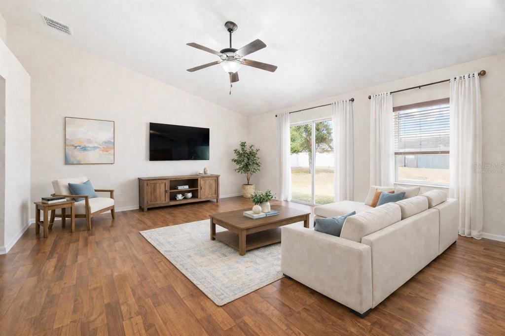 A living room with wood floors, a sectional sofa, a television, and sliding glass doors — 1131 HIGHLAND MEADOWS STREET, DAVENPORT, FL
