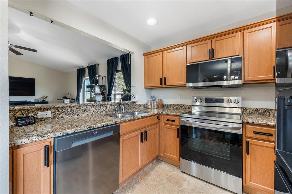 A kitchen with wood cabinets, granite countertops, and stainless steel appliances — 1131 HIGHLAND MEADOWS STREET, DAVENPORT, FL