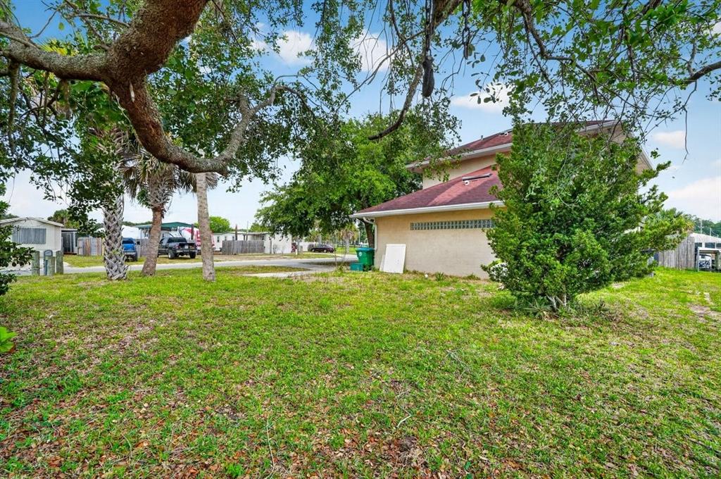 A grassy yard with trees and a tan house with a red roof — 124 RANDLE AVENUE, OAK HILL, FL