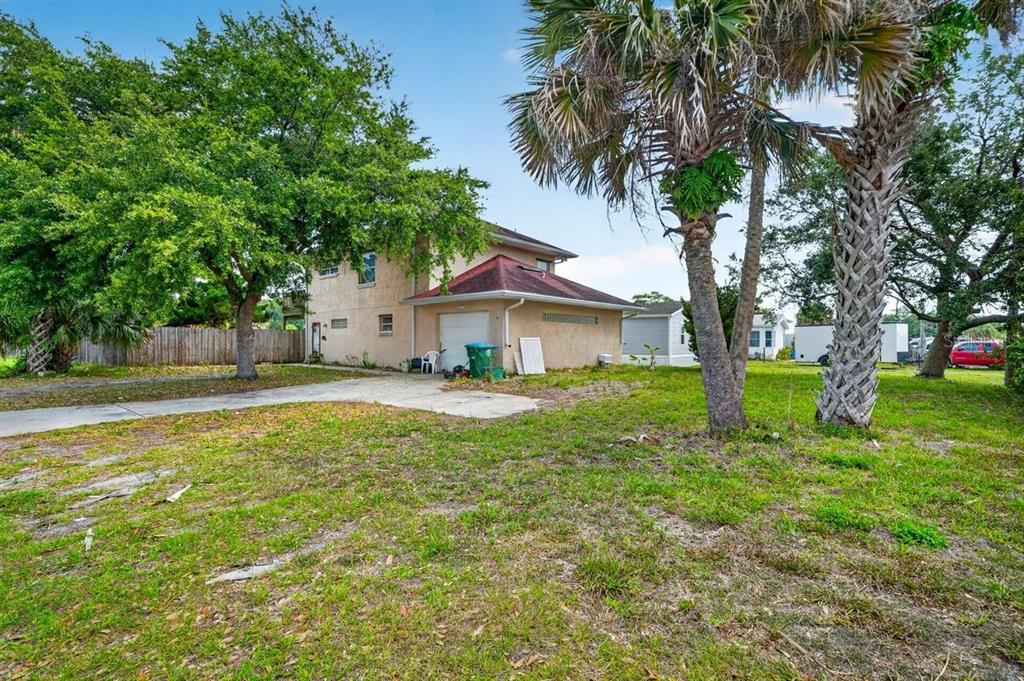 A two-story house with a tan exterior, a red-roofed garage, and a large front yard — 124 RANDLE AVENUE, OAK HILL, FL