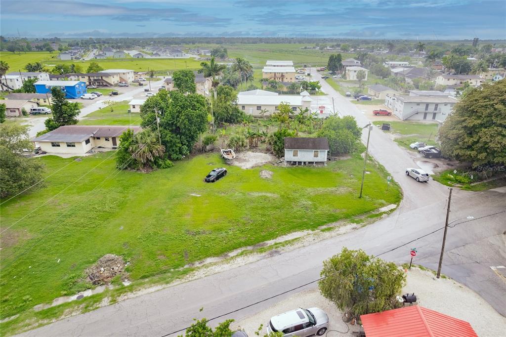 An aerial view shows a vacant grassy lot with a small house and a car — 601 SW 6TH STREET, BELLE GLADE, FL