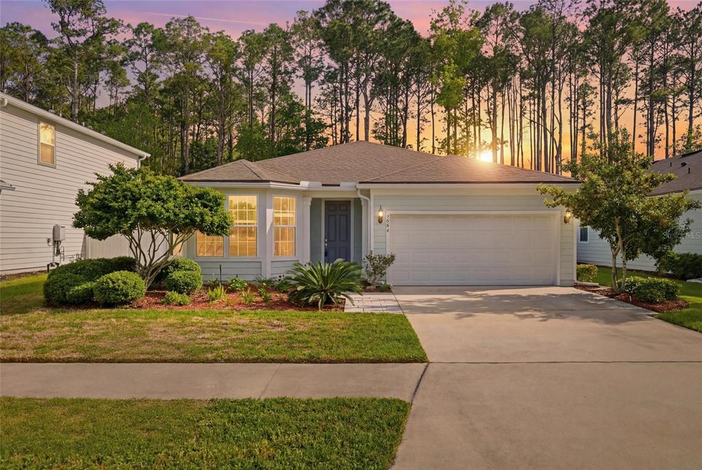 A single-story house with a two-car garage and a landscaped front yard at sunset — 4594 FARMHOUSE GATE TRAIL, JACKSONVILLE, FL
