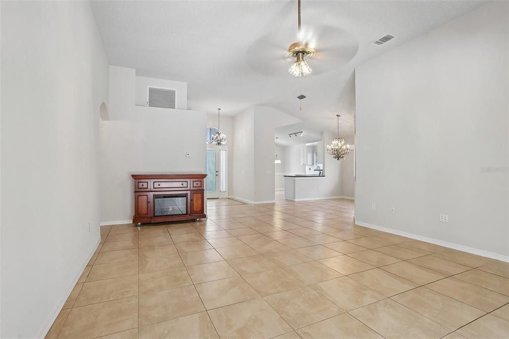 A spacious living area with tile flooring, a fireplace console, and an open kitchen — 10216 CHARLESTON CORNER ROAD, TAMPA, FL