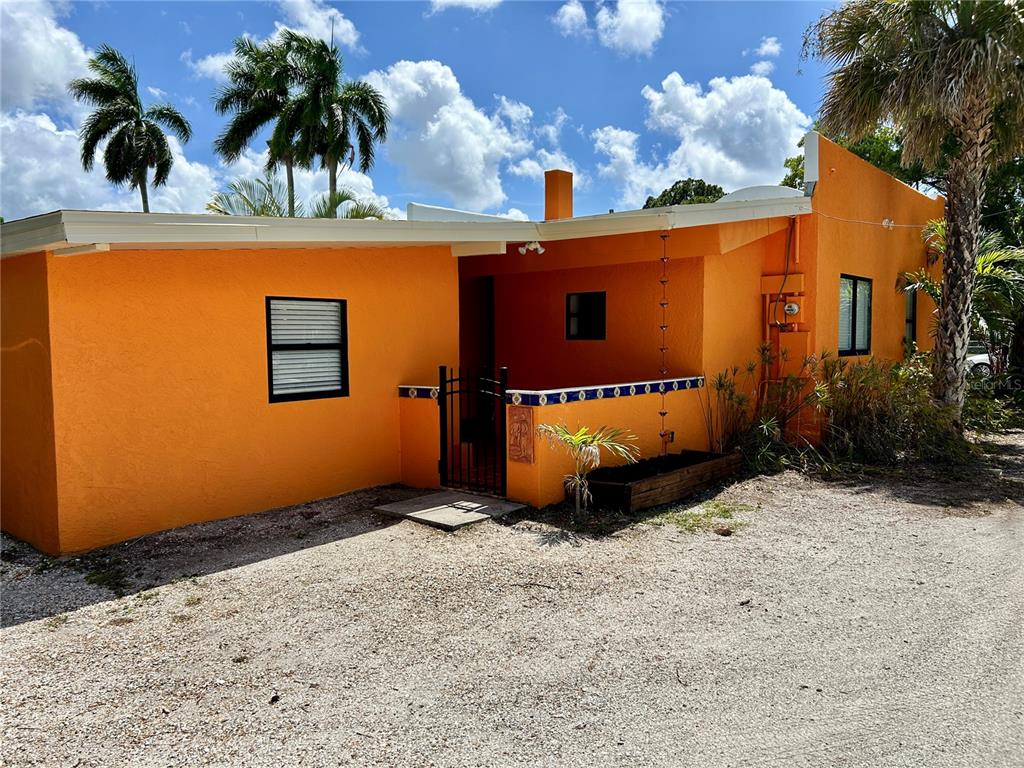 A bright orange, single-story house with a gated entryway and a gravel driveway — 1315 24TH ST W, BRADENTON, FL