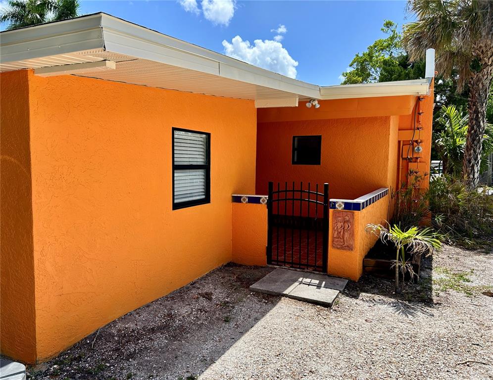 An orange stucco house exterior features a small gated courtyard and a single window — 1315 24TH ST W, BRADENTON, FL