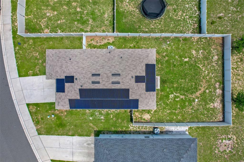 An aerial view shows a house with solar panels on the roof and a fenced yard — 479 JACKS WAY, DAVENPORT, FL