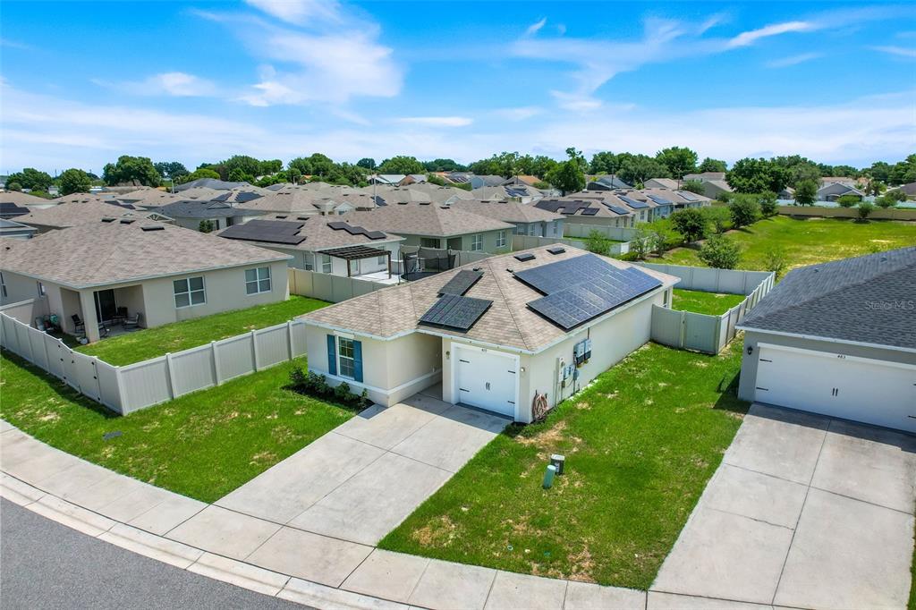An aerial view shows a single-story house with solar panels on the roof and a driveway — 479 JACKS WAY, DAVENPORT, FL