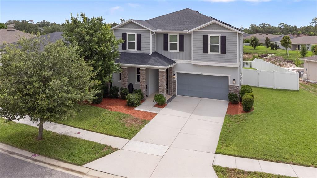 A two-story suburban house with gray siding, a stone-accented porch, and a two-car garage — 12500 ASTON DRIVE, HUDSON, FL