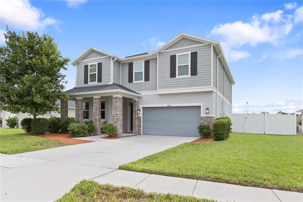 A two-story house with gray siding, stone accents, and a two-car garage — 12500 ASTON DRIVE, HUDSON, FL