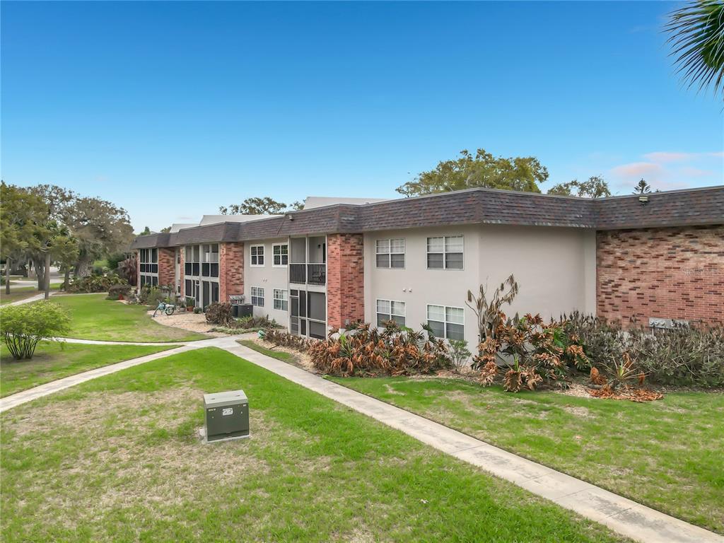 A two-story apartment building with brick accents and a flat roof sits on a lawn — 3800 SAXON DRIVE UNIT B13, NEW SMYRNA BEACH, FL