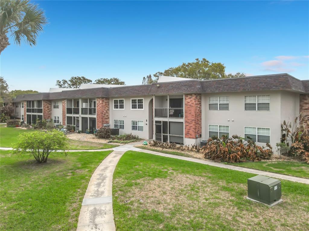 A two-story apartment building with brick accents, screened balconies, and a concrete walkway — 3800 SAXON DRIVE UNIT B13, NEW SMYRNA BEACH, FL