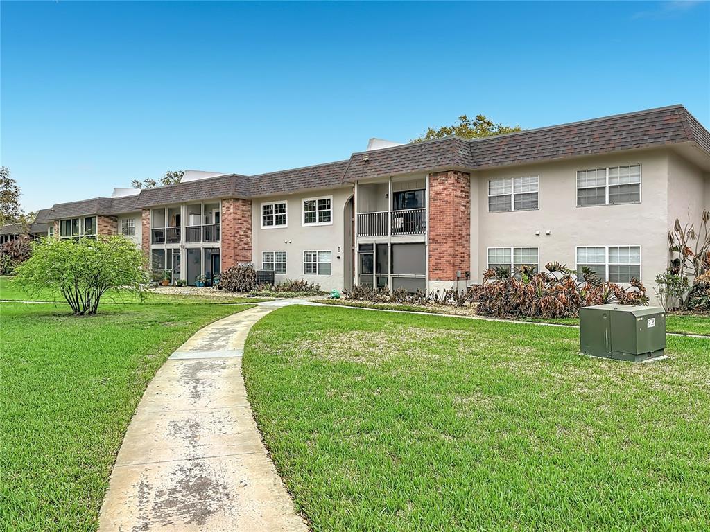 A two-story apartment building with brick accents and a concrete walkway across a lawn — 3800 SAXON DRIVE UNIT B13, NEW SMYRNA BEACH, FL
