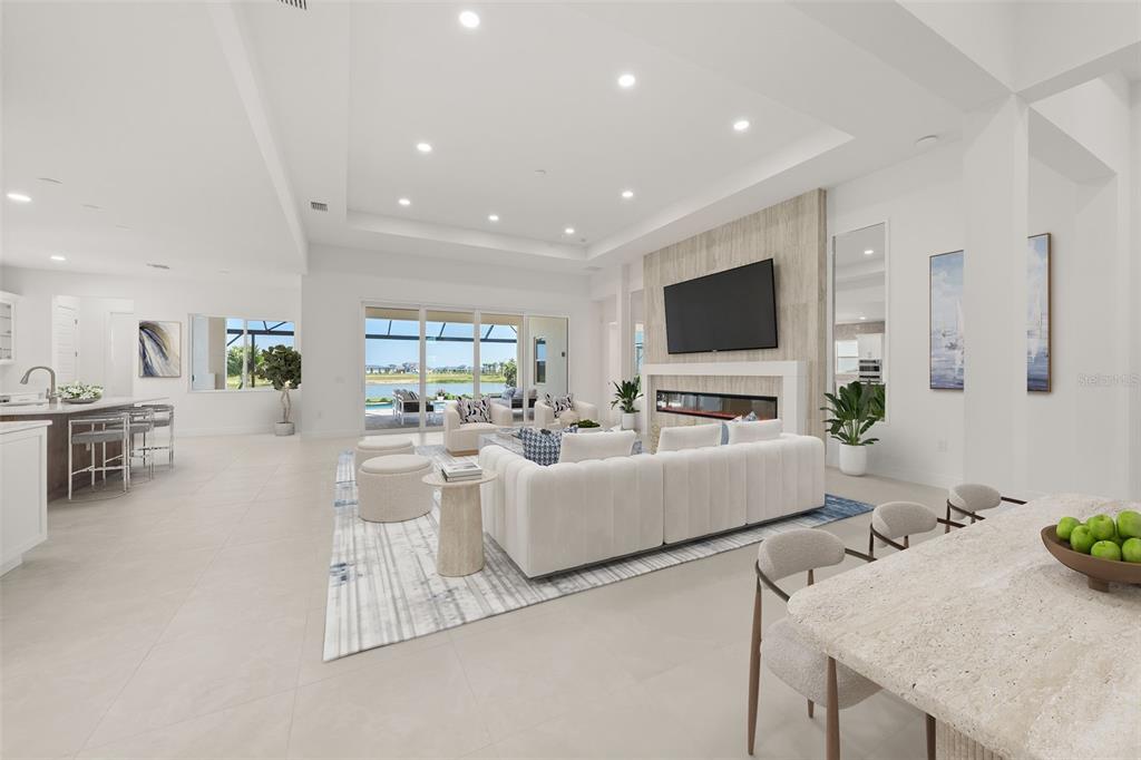 A bright, open-concept living room features a fireplace, white sofa, and large sliding glass doors — 844 BLUE SHELL LOOP, SARASOTA, FL