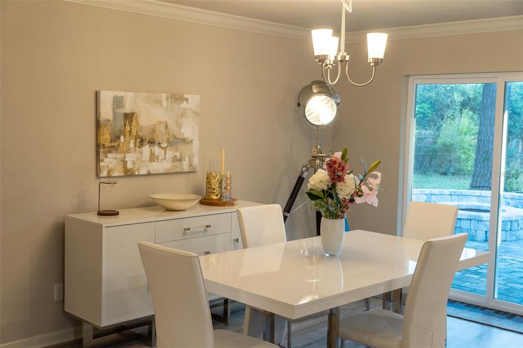 A dining room features a white table, matching chairs, a sideboard, and a tripod floor lamp — 8221 SW 13TH ROAD, GAINESVILLE, FL